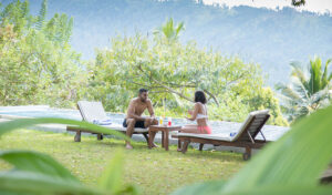 Couple relaxing on sun loungers outdoors with a scenic green mountain view